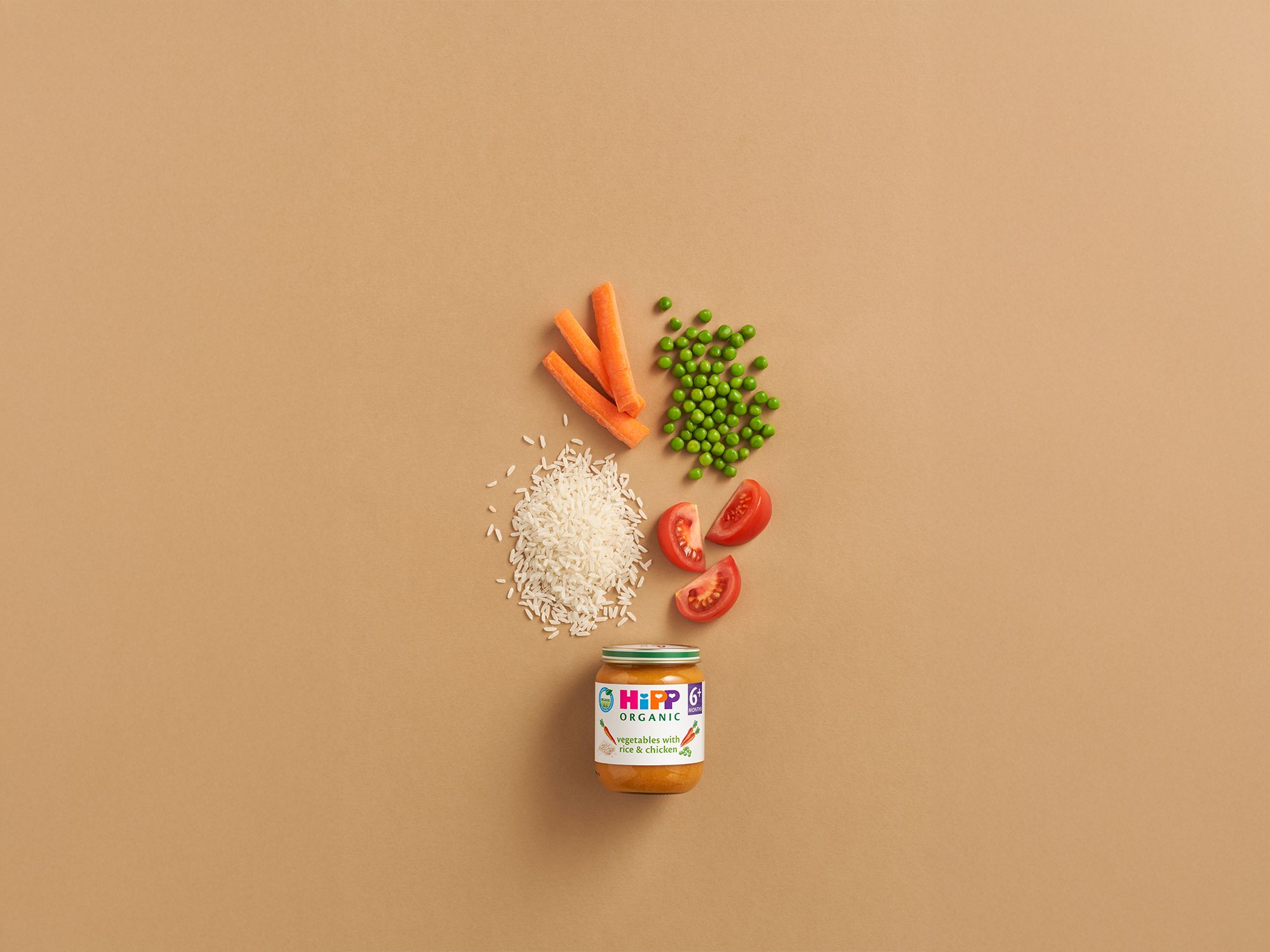 HiPP Organic Vegetables with Rice & Chicken jar with carrots, peas, rice and tomato pieces on a neutral background