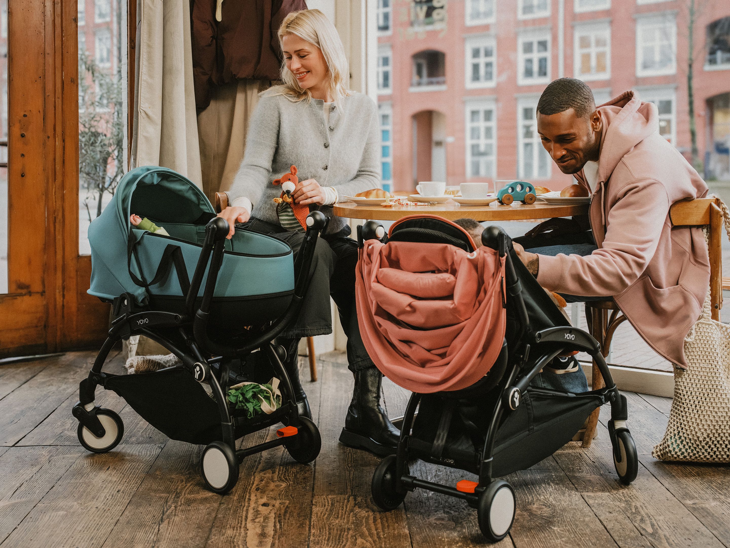 Frau und Mann sitzen mit zwei Kinderwägen