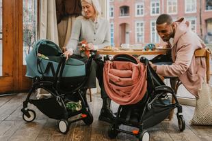 Frau und Mann sitzen mit zwei Kinderwägen