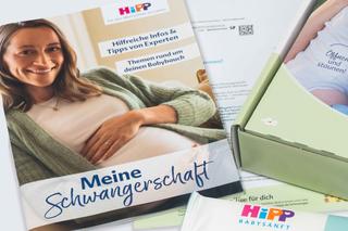 Schwangere Frau mit grünem Strickcardigan hält ihren Bauch vor einem Magazin mit der Überschrift 'Meine Schwangerschaft'