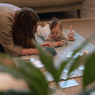 Mum reading development cards to baby