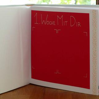 Ein roter rechteckiger Abschnitt in einem Buch mit dem Text "1. Woche Mit Dir" in weißer Schreibschrift.