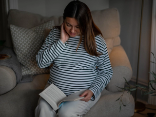 Expecting mum sat on sofa reading book