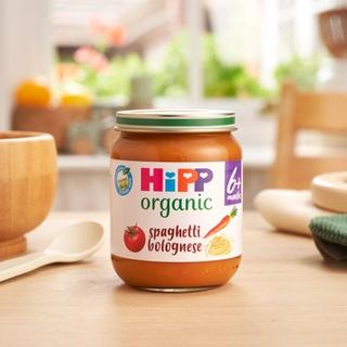 HiPP Organic Spaghetti Bolognese 6 months+ on a dining table next to a bowl and spoon