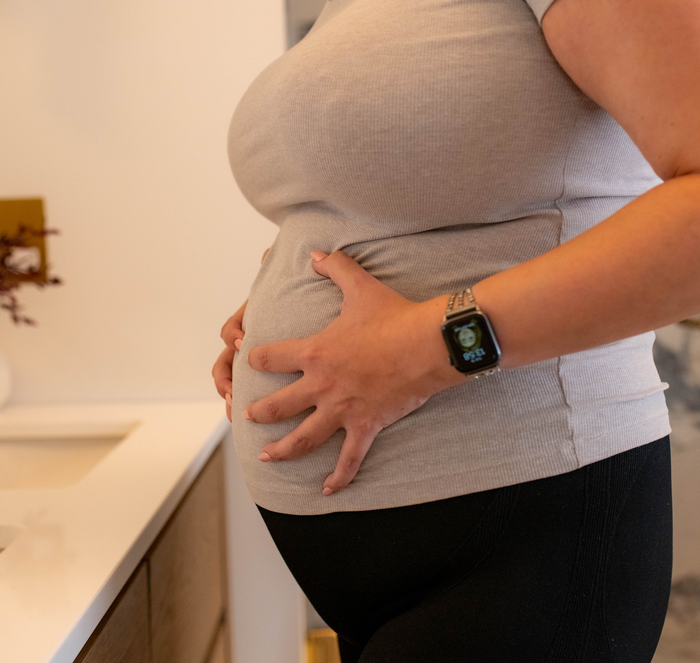 Shot from the shoulder below of a pregnant woman holding bump in pain as labor begins