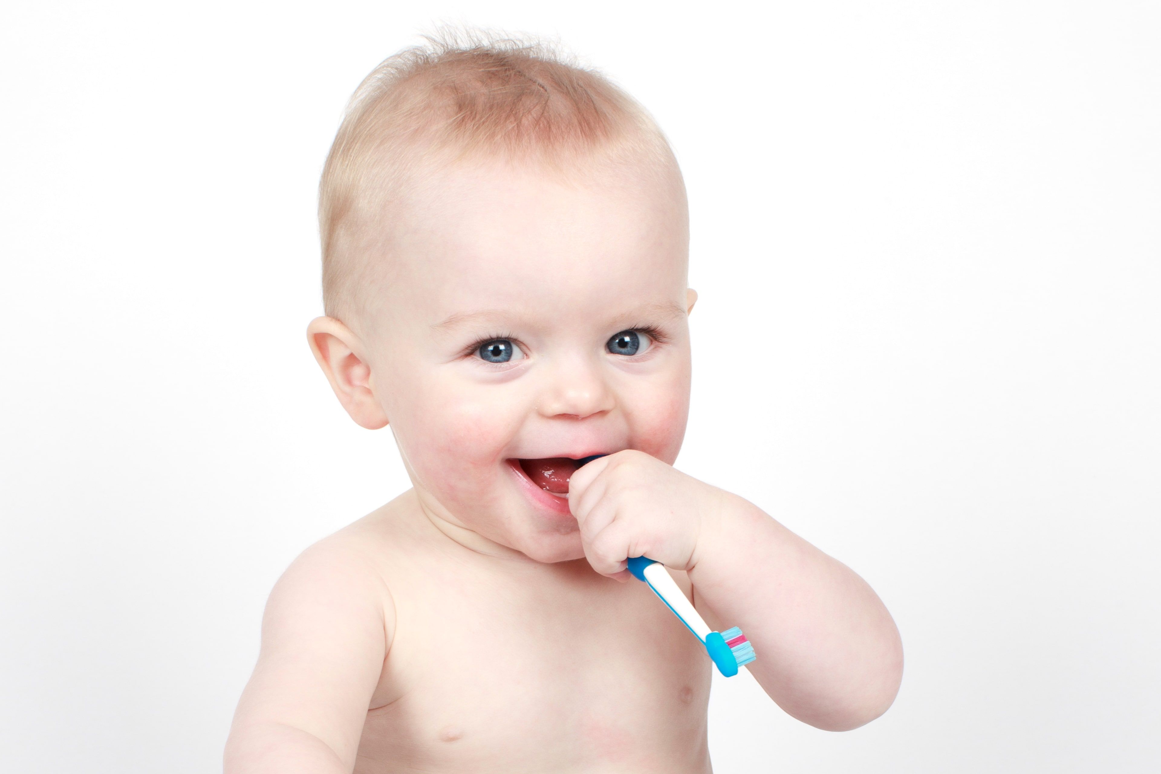 Ein Baby mit blauen Augen, das auf einer Zahnbürste kaut.