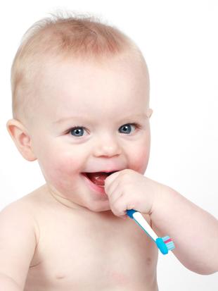 Ein Baby mit blauen Augen, das auf einer Zahnbürste kaut.