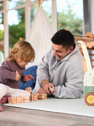 Dad playing with lettered blocks with his toddler