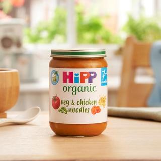 HiPP Organic Veg & Chicken Noodles jar on a dining table next to a spoon and bowl