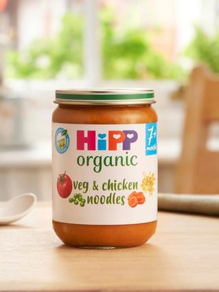 HiPP Organic Veg & Chicken Noodles jar on a dining table next to a spoon and bowl