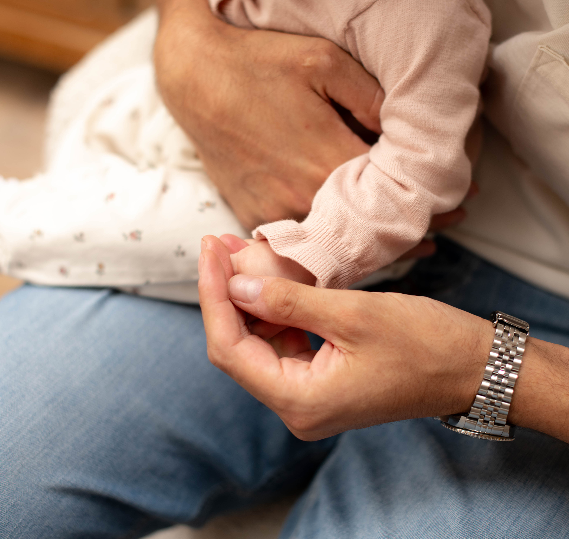 Close up of baby holding onto dad's finger