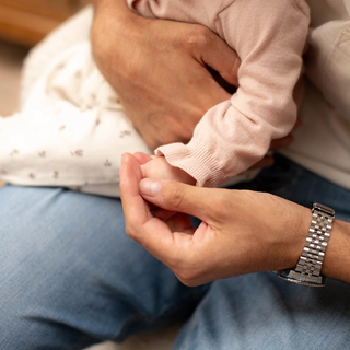 Close up of baby holding onto dad's finger