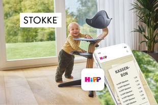 Lächelndes Baby am STOKKE Nomi Hochstuhl neben einem Smartphone mit HiPP App und Kassenbon