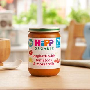 HiPP Organic Spaghetti with tomatoes & mozzarella on a dining table next to a bowl and spoon