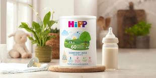 HiPP Organic comfort milk powder tin next to a milk bottle on a kitchen worktop