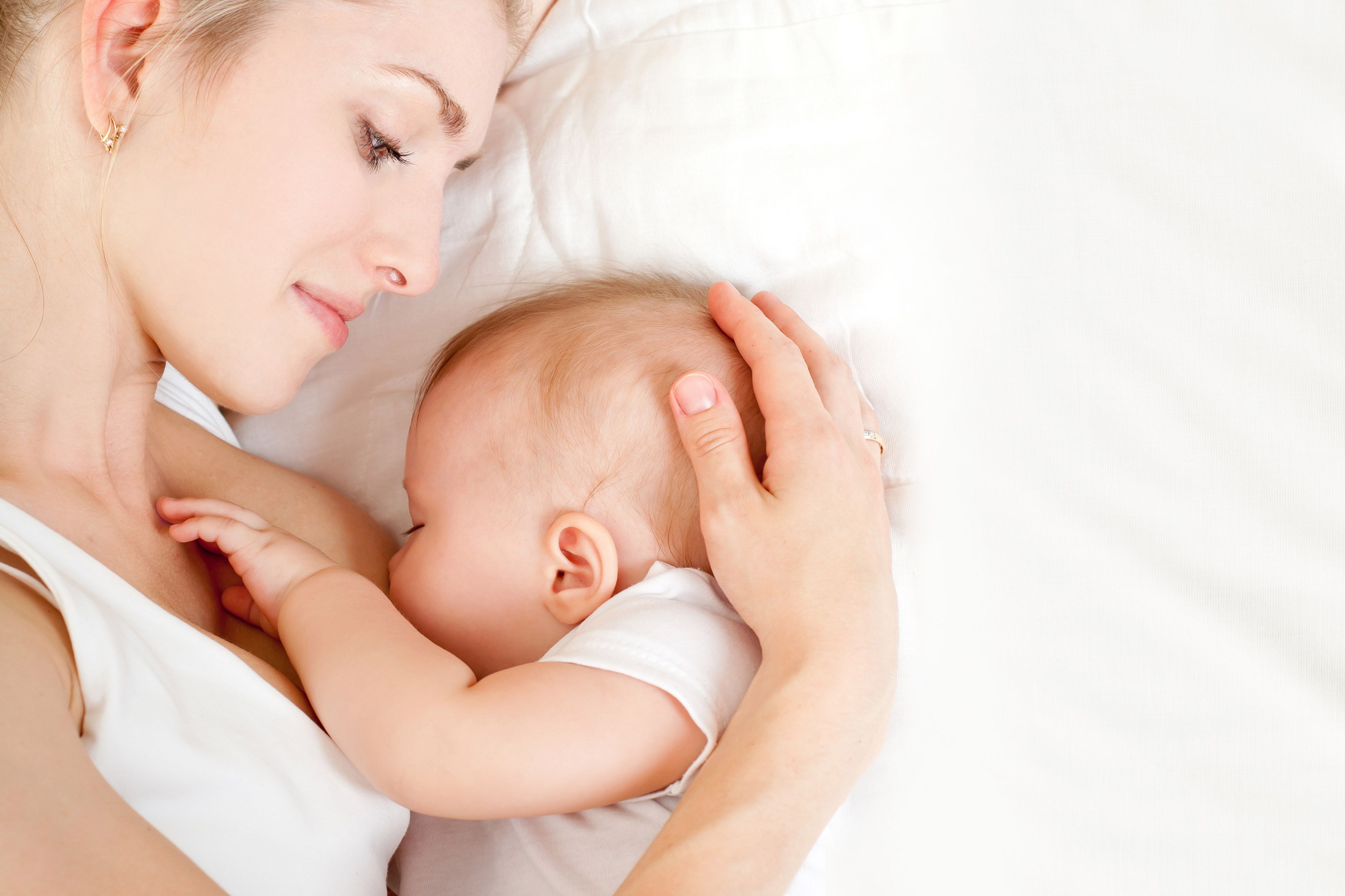 Ein zärtlicher Moment zwischen einer Mutter und ihrem Baby, in dem die Hand der Mutter sanft den Kopf des Babys berührt.