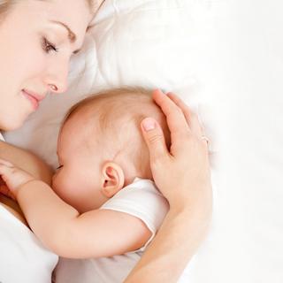 Ein zärtlicher Moment zwischen einer Mutter und ihrem Baby, in dem die Hand der Mutter sanft den Kopf des Babys berührt.