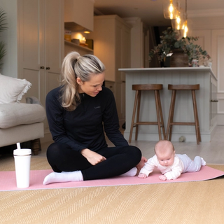 Mum preparing to exercise with baby having tummy time next to her