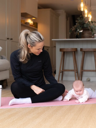 Mum preparing to exercise with baby having tummy time next to her