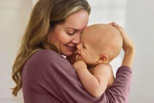 Frau hält ein Baby eng an sich und stützt den Kopf des Babys mit der Hand
