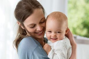 Ein freudiger Moment zwischen einer Frau und einem Baby, wobei die Frau das Baby an sich drückt und beide ein zärtliches Lächeln teilen.