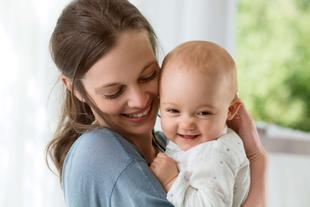 Ein freudiger Moment zwischen einer Frau und einem Baby, wobei die Frau das Baby an sich drückt und beide ein zärtliches Lächeln teilen.