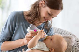 Eine Frau, die ihr Baby mit der Flasche füttert, mit einem sanften und liebevollen Gesichtsausdruck.