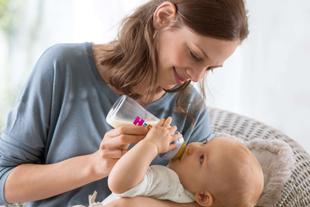 Eine Frau, die ihr Baby mit der Flasche füttert, mit einem sanften und liebevollen Gesichtsausdruck.