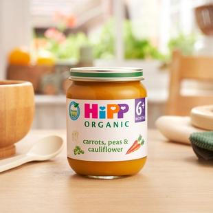 HiPP Organic Carrots, Peas & Cauliflower jar on a dining table next to a bowl and spoon