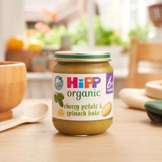 HiPP Organic Cheesy Potato & Spinach Bake on a dining table next to a bowl and spoon