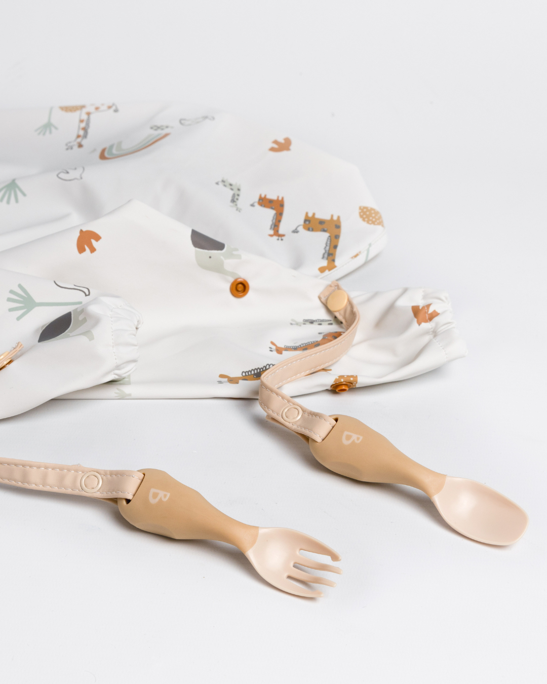Bibado bib with handi weaning cutlery attached lying on a white background