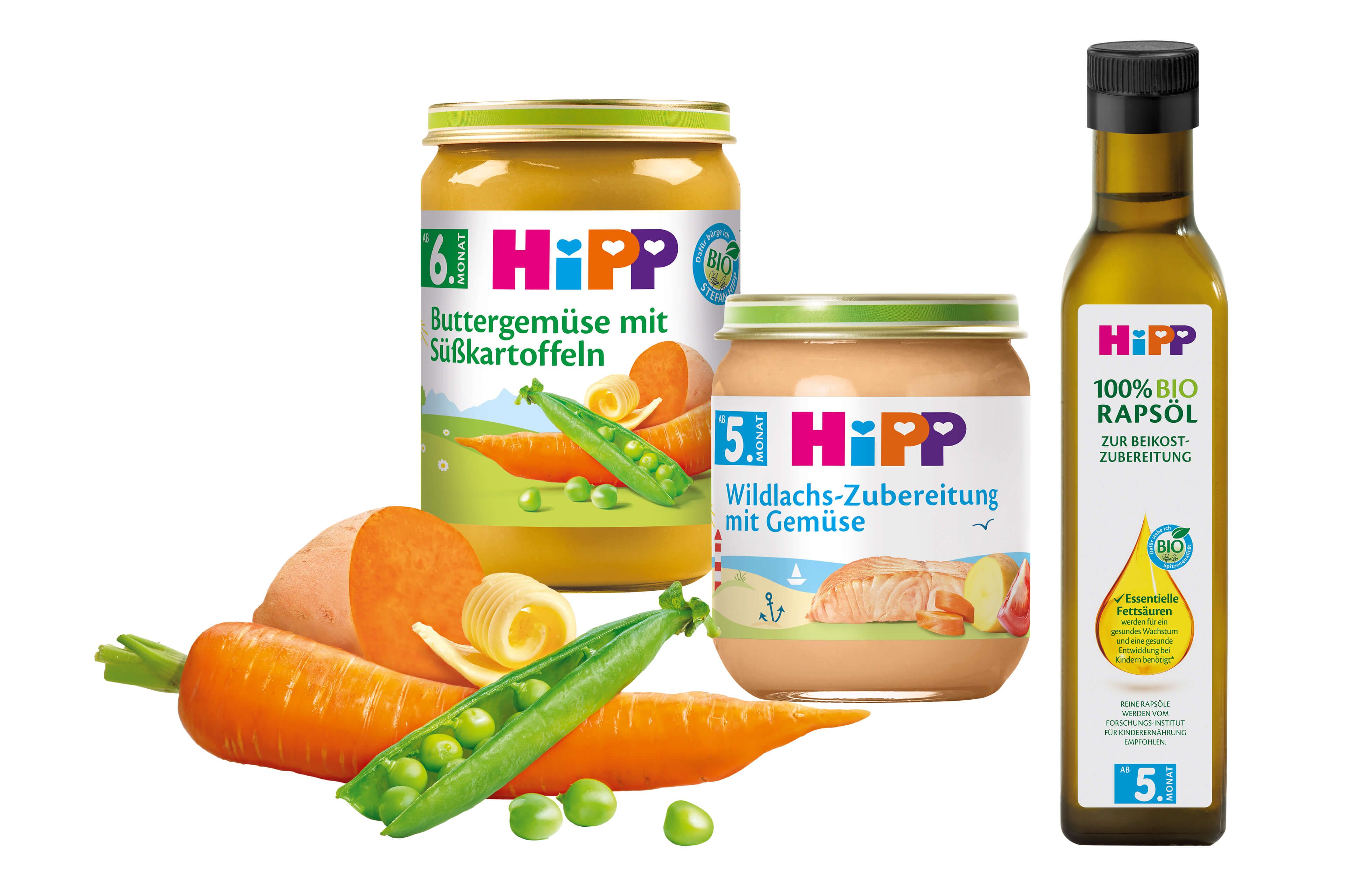 Eine Reihe von Babynahrungsprodukten der Marke "Hipp", darunter Gläser mit Karotten- und Orangenpüree und eine Flasche Olivenöl.