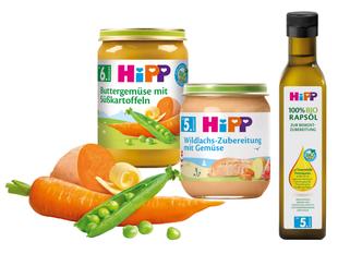 Eine Reihe von Babynahrungsprodukten der Marke "Hipp", darunter Gläser mit Karotten- und Orangenpüree und eine Flasche Olivenöl.