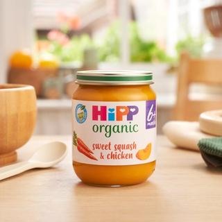 HiPP Organic Sweet Squash & Chicken on a dining table next to a bowl and spoon