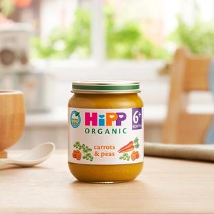 HiPP Organic Carrots & Peas on a dining table next to a bowl and spoon