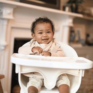 Smiling baby sitting in a high chair at home, ready to explore new weaning flavours