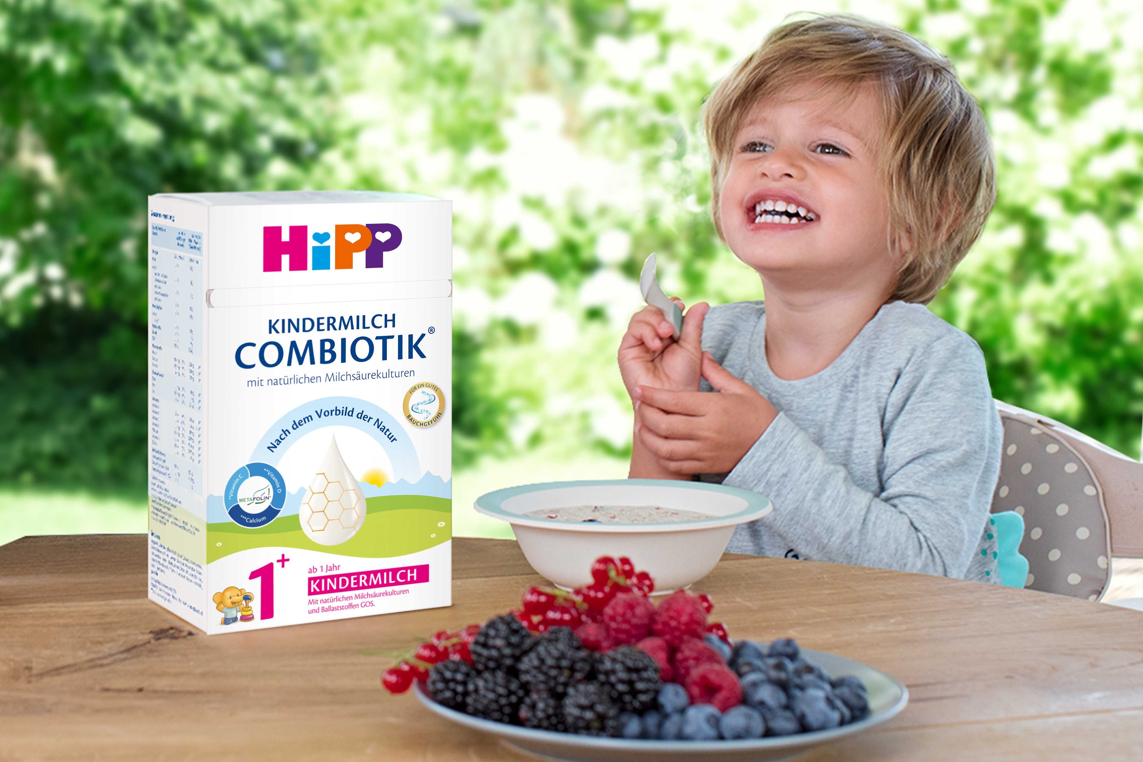 Lachendes Kleinkind frühstückt mit HiPP Kindermilch COMBIOTIK®, Beerenobst und Getreidebrei für eine ausgewogene Nährstoffversorgung.