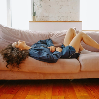 Woman lying on sofa in pain holding stomach