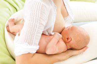 Eine Mutter, die ihr Baby bequem auf einer weichen Unterlage stillt.