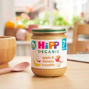 HiPP Organic Apple & Banana Crumble Jar on a dining table next to a bowl and spoon