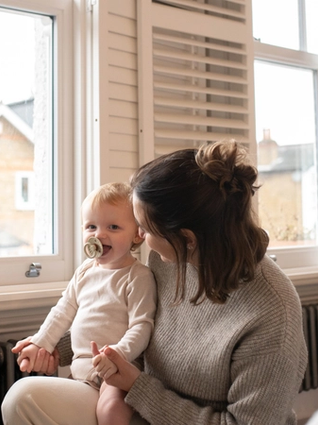Mum and baby laughing together whilst getting ready