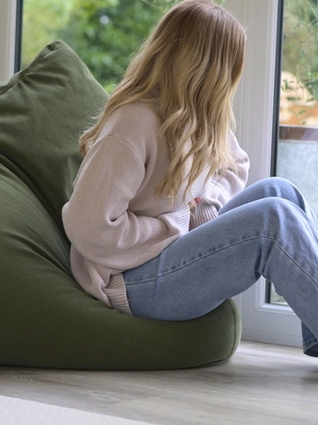 Woman holding stomach whilst looking out of window