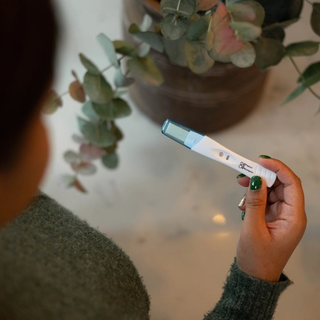 Person holding a pregnancy test with two visible lines, indicating a positive result.