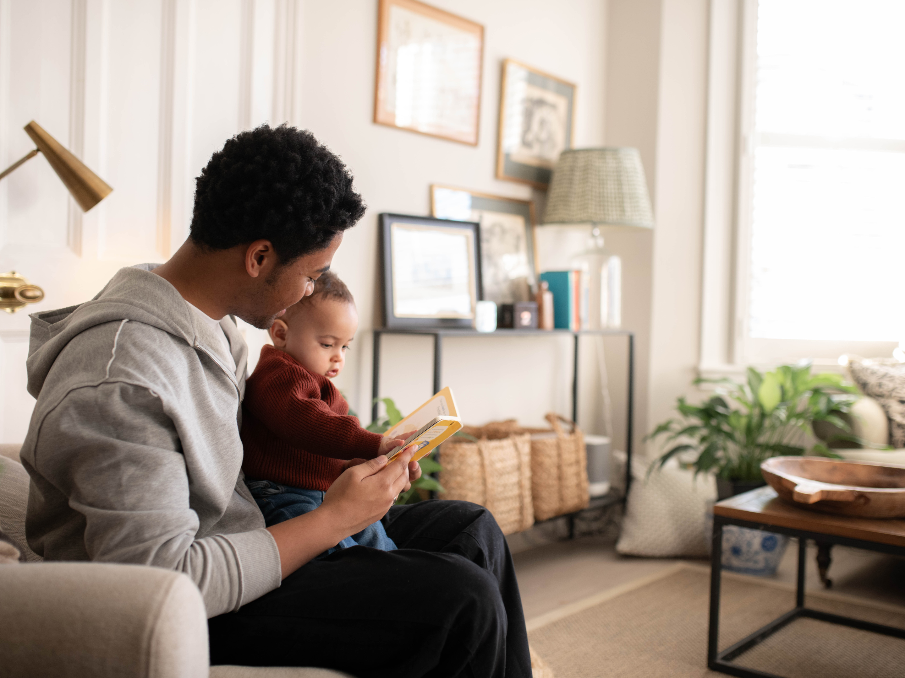 Baby sat on dad's lap whilst reading a book together