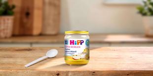 HiPP Guten Morgen Früchte-Joghurt-Müesli Bio-Gläschen mit Löffel auf einem Holztisch in heller Küche