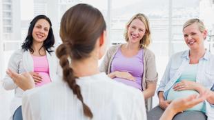 Vier Frauen in einem Raum, drei von ihnen schwanger, unterhalten sich mit einer Frau, die von der Kamera wegschaut.