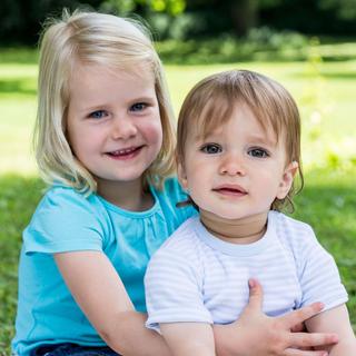 Zwei kleine Kinder, ein Mädchen und ein Junge, im Freien in einem Park.