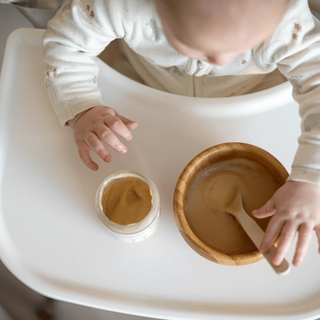 Baby eating from a baby food jar