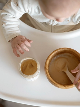 Baby eating from a baby food jar