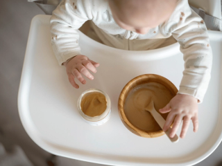 Baby eating from a baby food jar